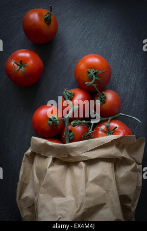 Tomaten in Papiertüte auf Schiefer Hintergrund. Ansicht von oben Stockfoto