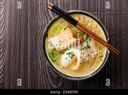 Asiatische Miso Ramen-Nudeln mit Ei, Tofu und Enoki in Schüssel auf grauem Hintergrund aus Holz Stockfoto