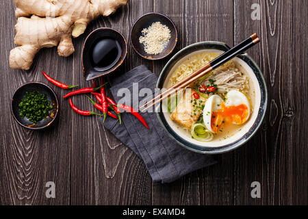 Asiatische Miso Ramen-Nudeln mit Ei, Tofu und Enoki in Schüssel auf grauem Hintergrund aus Holz Stockfoto