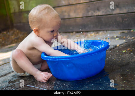 Niedliche Baby mit einer Wanne mit Wasser spielen Stockfoto