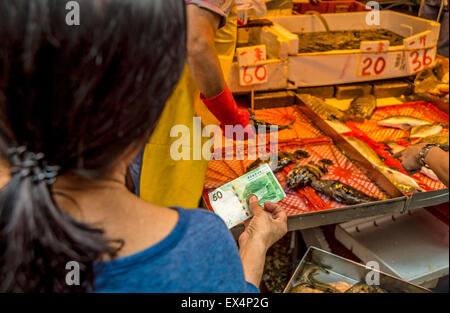 Kunden zahlen für Fisch und Meeresfrüchte auf dem Markt in Hong-Kong Stockfoto