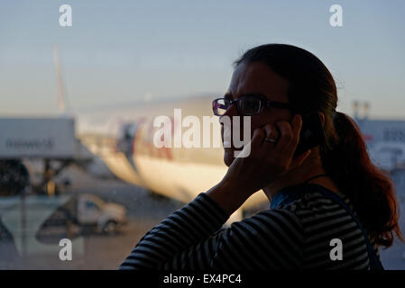 Eine Frau mit einem Handy an einem Flughafen Stockfoto