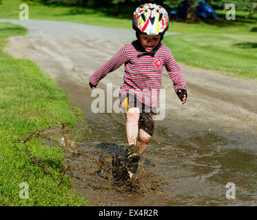 Ein Junge (3 Jahre alt) junge in einer schlammigen Pfütze springen Stockfoto