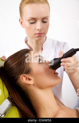 Porträt von attraktiven schöne junge Brünette Frau mit einer anregenden Gesichtsbehandlung von einem Therapeuten auf dem Tisch Stockfoto