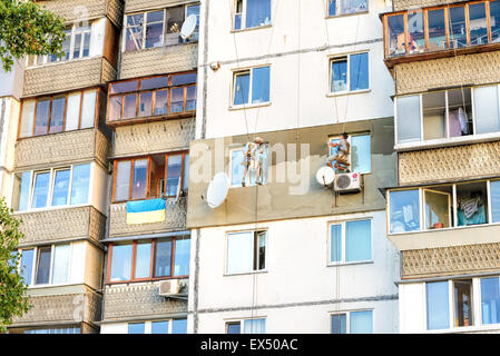 Kiew, Ukraine - 30. Juni 2015: Fassade Stuckateure bauen die äußere Wärmedämmung einer Wohnung sitzen auf der Schaukel Stockfoto