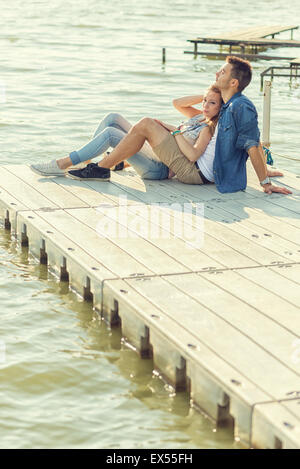 Paar in Liebe sitzen auf dem Pier, umarmen Stockfoto