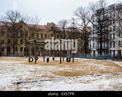Berlin Arkonaplatz schneebedeckte Kinderspielplatz, Park, Schaukeln und Mehrfamilienhäuser im Winter Stockfoto