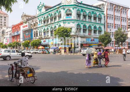 Yangon, Myanmar-Mai 4. 2014: Menschen, die die Straße überqueren. Sonnenschirme werden häufig von Menschen verwendet, um der heißen Sonne zu schützen. Stockfoto