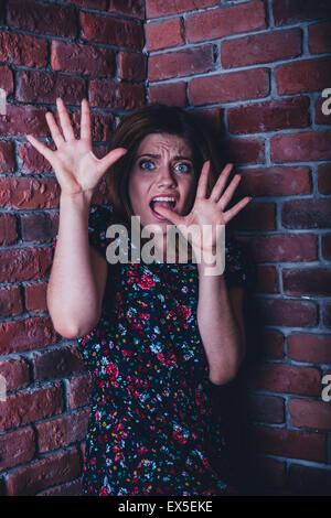 Verängstigte junge Frau steht in der Ecke der Mauer Stockfoto
