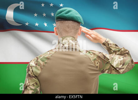 Soldat im Hut vor Nationalflagge Reihe - Usbekistan Stockfoto