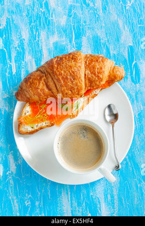 Croissant mit geräuchertem Lachs und Frischkäse und Tasse Kaffee Stockfoto