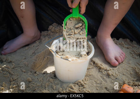 Jungen spielen im Sandkasten mit Eimer und Spaten Stockfoto