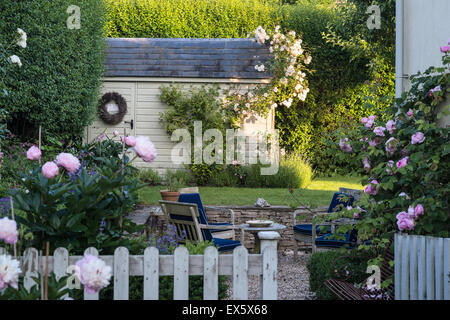 Hölzerne Schuppen im Garten mit Rosen und Pfingstrosen Stockfoto