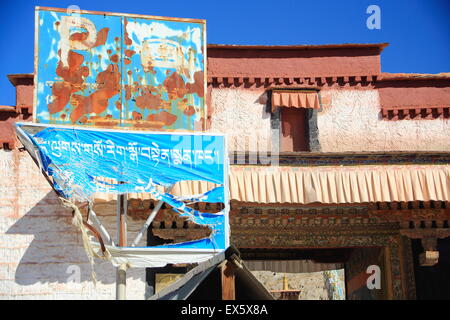 Rostige alte metallische Schild und zerrissene Stoff Informationstafel am Eingang zu den 1418 AD.built Pelkhor Chode-Kloster. Tibet. Stockfoto