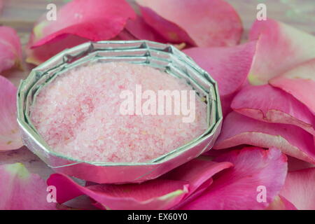 Rosa aromatisch Badesalz auf einem Tisch dekoriert mit Rosenblättern Stockfoto