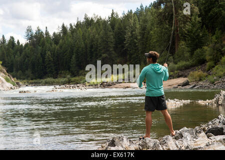 Junge Fliegenfischer Gießen seinen Stab in einen Fluss Montana Stockfoto