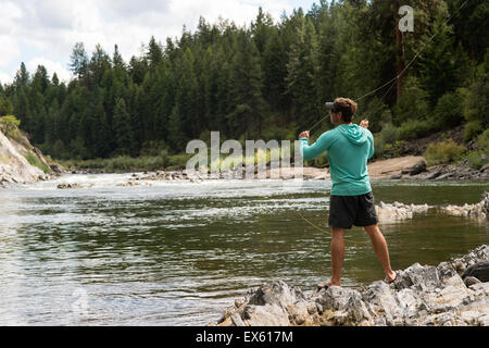 Junge Fliegenfischer Gießen seinen Stab in einen Fluss Montana Stockfoto