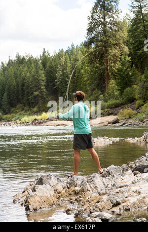 Junge Fliegenfischer Gießen seinen Stab in einen Fluss Montana Stockfoto