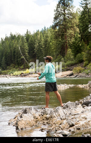 Junge Fliegenfischer Gießen seinen Stab in einen Fluss Montana Stockfoto