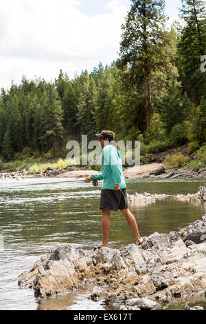 Junge Fliegenfischer Gießen seinen Stab in einen Fluss Montana Stockfoto