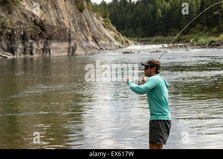 Junge Fliegenfischer Gießen seinen Stab in einen Fluss Montana Stockfoto