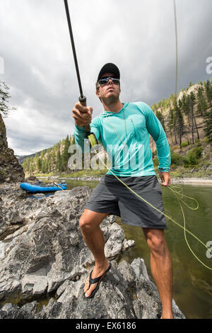 Junge Fliegenfischer Gießen seinen Stab in einen Fluss Montana Stockfoto