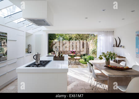 Offene weiße moderne Küche mit benutzerdefinierten aus Tabelle von Kalk und Eiche und Kunststoff Eames Stühle Stockfoto