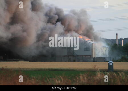 Rainham, London, UK. Dienstag, 7. Juli 2015. Über 80 Feuerwehrleute bekämpfen Brand in einer Palette Hof in Rainham. 12 Feuerwehrautos aus drei Feuerwehren wurden um ca. 20:00 Dienstag Abend in der Szene genannt. Kent und Essex, Feuerwehr und Rettungsdienste wurden gerufen, um die Londoner Feuerwehr unterstützen, bekämpfen das Feuer. Ein Stapel von Paletten und etliche Gebäude sind vermutlich in das Feuer. Form, die der Brand kilometerweit sehen konnte, wie Winde angefacht zu rauchen. Es gibt keine gemeldeten Verletzungen und die Ursache für den Brand ist noch nicht bekannt. Stockfoto