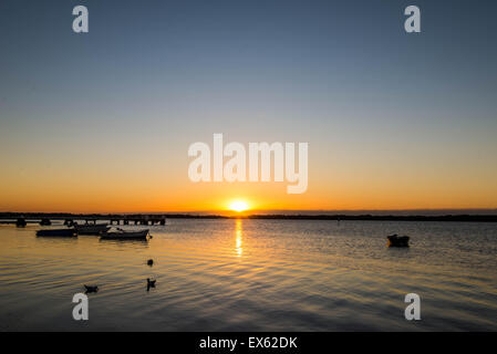 Sonnenaufgang über dem Wasser am Steg Angeln mit Vögel und Boote auf dem Wasser Stockfoto