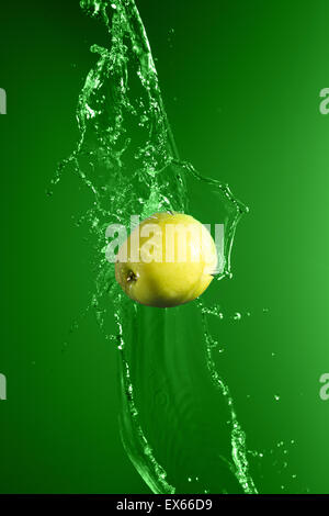 Grüner Apfel mit Spritzwasser auf grünem Hintergrund Stockfoto