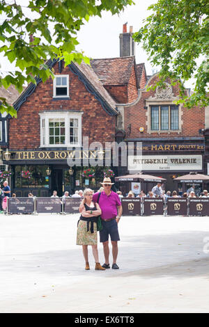 Paar steht auf dem Marktplatz mit The Ox Row Inn und Patisserie Valerie hinter in Salisbury im Juni Stockfoto