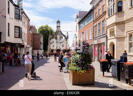 Straßenszene mit Blick auf alte 16thc Market Cross mit Menschen beim Einkaufen in Chichester Stadtzentrum entfernt. East Street Chichester West Sussex England UK Großbritannien Stockfoto