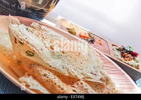 South Indian Rava Dosa zusammen mit Kokos-Chutney und Sambhar gemacht von Gewürzen und Lenthils, serviert auf einem traditionellen Bambus-Teller Stockfoto