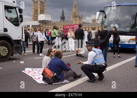 London, UK. 8. Juli 2015. Ein Polizist Gemeinschaft Unterstützung verhandelt mit Demonstranten, die Westminster Bridge während einer Protestaktion gegen den Haushalt blockiert haben. Gegen Sparpolitik und Behinderung Aktivisten aus Protest gegen was sie sehen, wie ein Haushalt, der verfolgt und verteufelt Leistungsempfänger, dann marschierte vorbei an Parlament und blockiert Westminster Bridge Credit mehrfarbige Kugeln in Whitehall vor Downing Street freigesetzt: Patricia Phillips/Alamy Live News Stockfoto