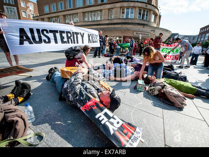 Exeter, Devon, UK. 8. Juli 2015. Menschen spielen tot während der Exeter Budget Aktionstag #AusterityKills in Exeter City Centre am 8. Juli 2015 in Bedford Square, Exeter, UK Credit: Clive Chilvers/Alamy Live News Stockfoto