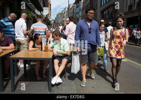 Sommer in London, England, Vereinigtes Königreich. Menschen trinken vor einem Pub auf einer belebten Ecke im Covent Garden. Dies ist einer der belebtesten Gegenden im West End. Stockfoto