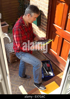 Handwerker mit dem iPad arbeiten bei Eingangstür des inländischen Haus für Sicherheit Wartung Reparatur Stockfoto