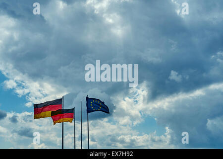 Zwei deutsche Fahnen Wind in eine Richtung und eine EU-Flagge weht in die entgegengesetzte Richtung, in der linken Ecke-o Stockfoto