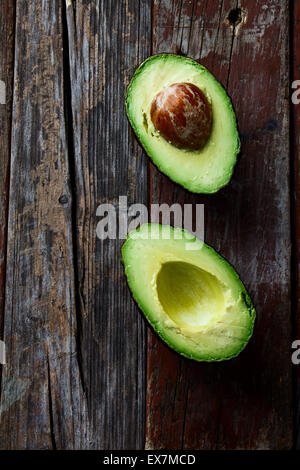 Halbierte Avocados auf rustikalen hölzernen Hintergrund. Ansicht von oben. Stockfoto