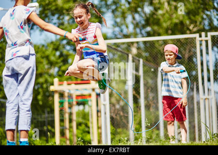 Glückliches Mädchen über überspringen Seil springen von ihren Freunden im Freien gehalten Stockfoto