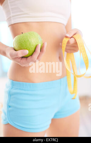 Schlanke weibliche Holding Messung Band und grüner Apfel Stockfoto
