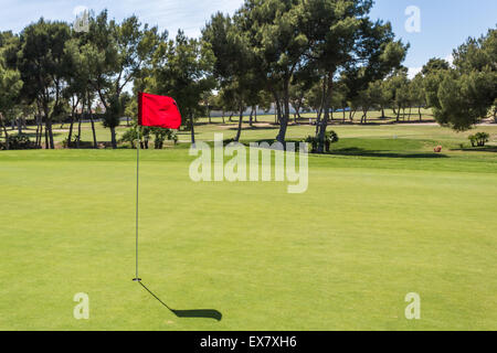 Rote Fahne im Loch auf einem grünen Golf-Feld Stockfoto