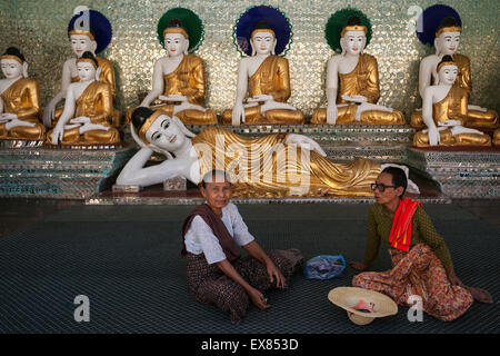 Zwei Frauen sitzen vor Statuen von Buddha, Shwedagon-Pagode, Yangon, Myanmar Stockfoto