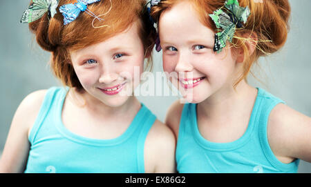 Lächelnd Rothaarige Zwillingsschwestern mit Schmetterling im Haar Stockfoto