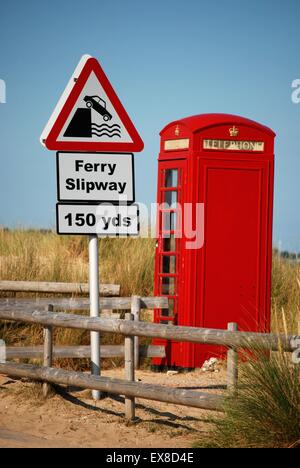 Rote Telefondose und Straßenschild auf der Slipway-Zufahrt zur Sandbanks Kettengliederfähre, Poole Harbour, Dorset, von der Purbeck-Seite. Stockfoto