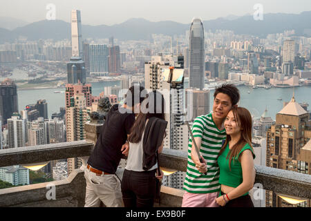 Junge asiatische paar mit einem Selfie-Stick vor Hong Kong Skyline vom Victoria peak