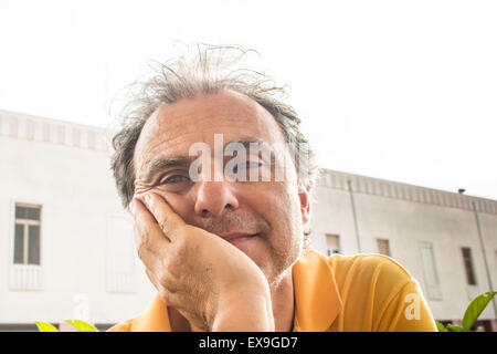 Nahaufnahme von hübsch stilvoll im mittleren Alter Sport Mann mit drei-Tage-Bart und Salz Cand Pfeffer Haar trägt ein gelbes Polo Shirt mit alten Gebäude im Hintergrund Stockfoto