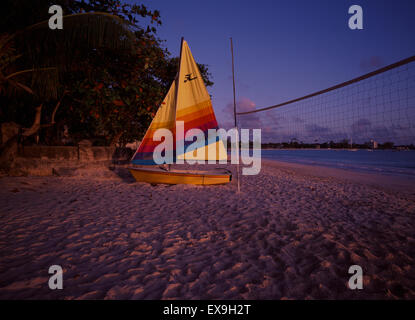 Kleines Segelboot in Carlisle Bay, Barbados bei Sonnenuntergang am Strand Stockfoto