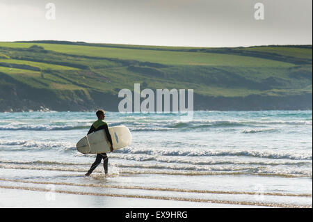 Ein Surfer zu Fuß in das Meer bei Crantock Beach in Newquay, Cornwall. Stockfoto