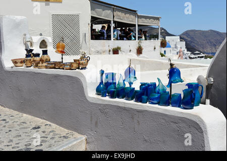 Schöne handgefertigte Glaswaren zeigen auf eine kleine Mauer vor einem Restaurant in Fira (Thira), Santorini, Griechenland. Stockfoto